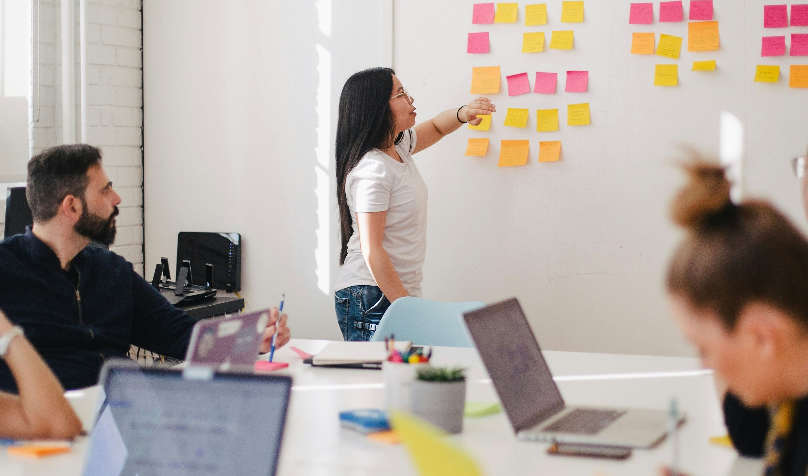 Gruppo di persone in una sessione di brainstorming con post-it colorati su una lavagna.