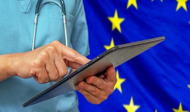 Medico che tiene in mano un tablet, sullo sfondo la bandiera europea