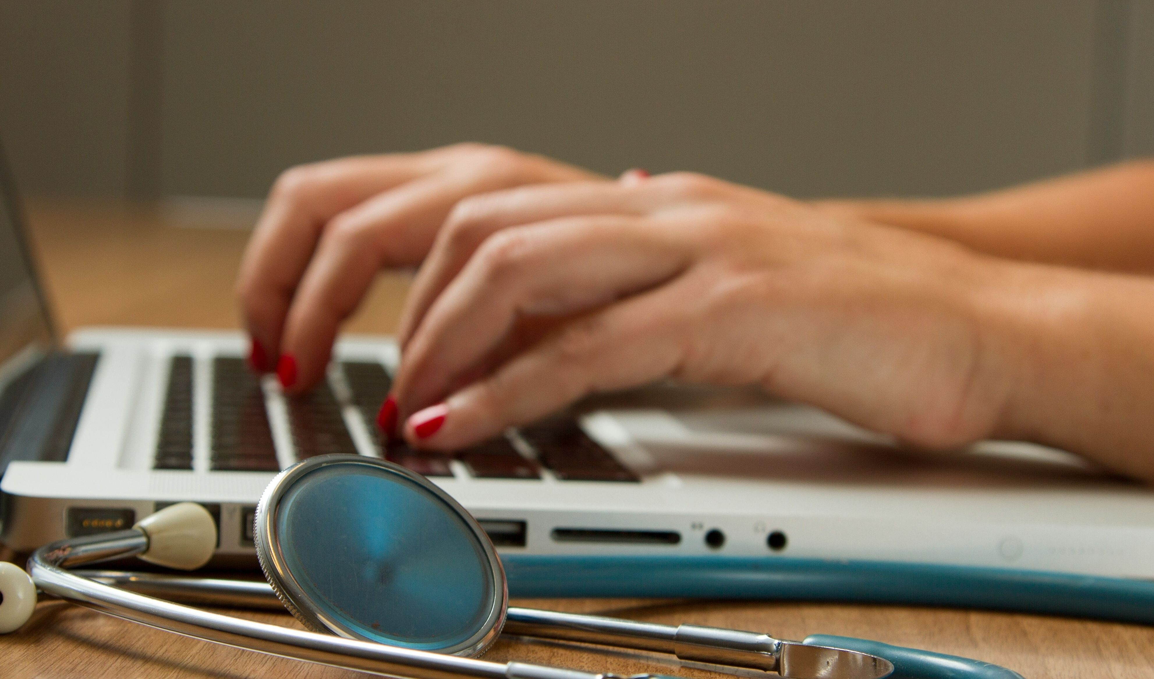 medico scrive su un pc, con accanto uno stetoscopio